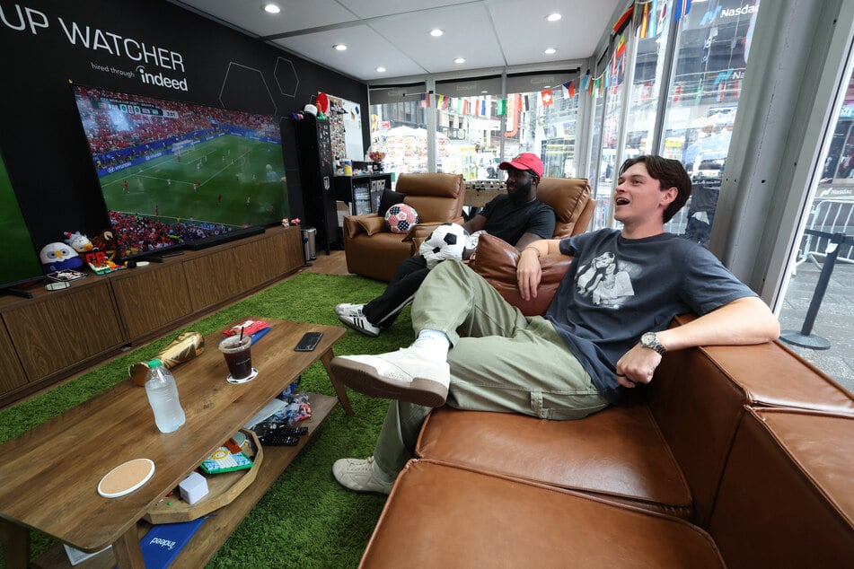 Austin Franklin (r.) and Kevin Akoto watch a 2026 World Cup match between Portugal and Uzbekistan from their transparent cube in Times Square on June 23, 2026.