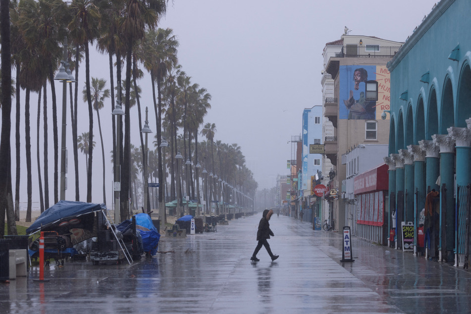 A person walks along an empty Venice Beach Boardwalk during the winter storm.