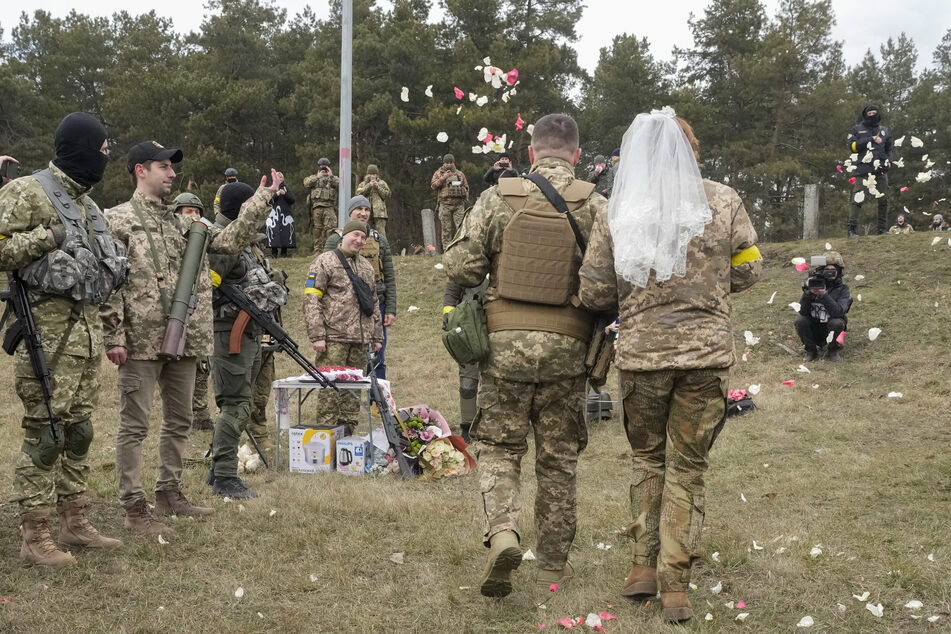 Soldaten werfen Rosenblätter über die frisch verheirateten Mitglieder der ukrainischen Territorialen Verteidigungskräfte während ihrer Hochzeitszeremonie an einem Kontrollpunkt in Kiew.