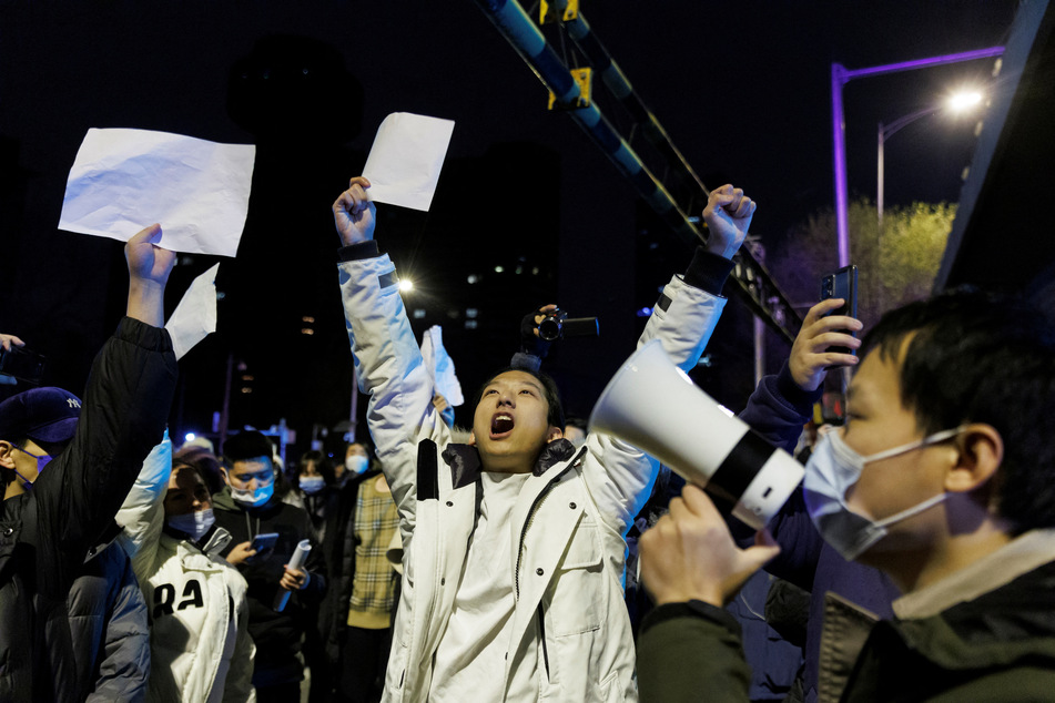 People in Beijing, China, hold white sheets of paper in protest over Covid-19 restrictions after a vigil for the victims of a fire in Urumqi.