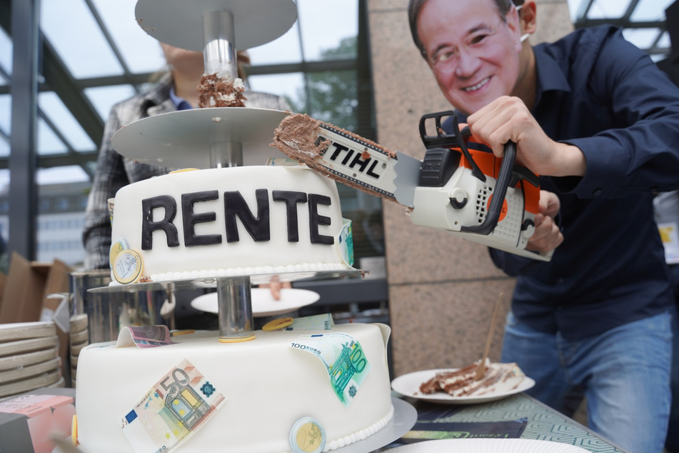 Bei einem außerordentlichen Bundesparteitag der FDP zersägt ein Mitglied der Jungen Liberalen mit einer Maske Laschets eine Torte mit der Aufschrift "Rente".