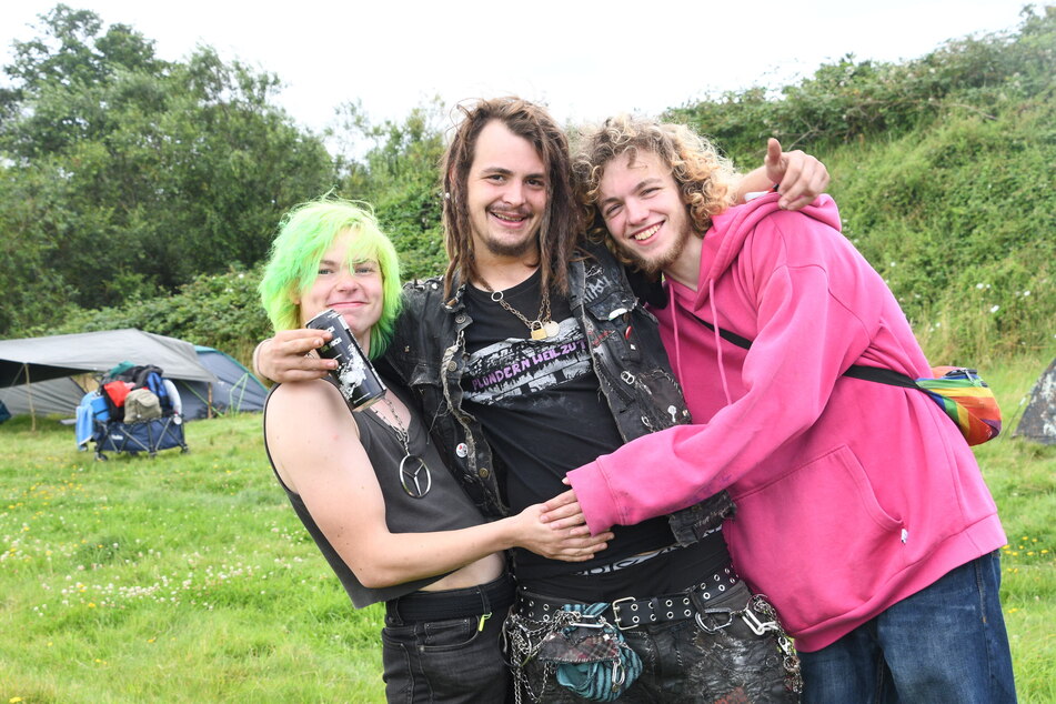 Die Protestcamp-Organisatoren Jonas Hötger (24, v. l.), Marvin Bederke (24) und Mikki (23) stehen auf einer Wiese vom Punk-Protestcamp "Aktion Sylt".