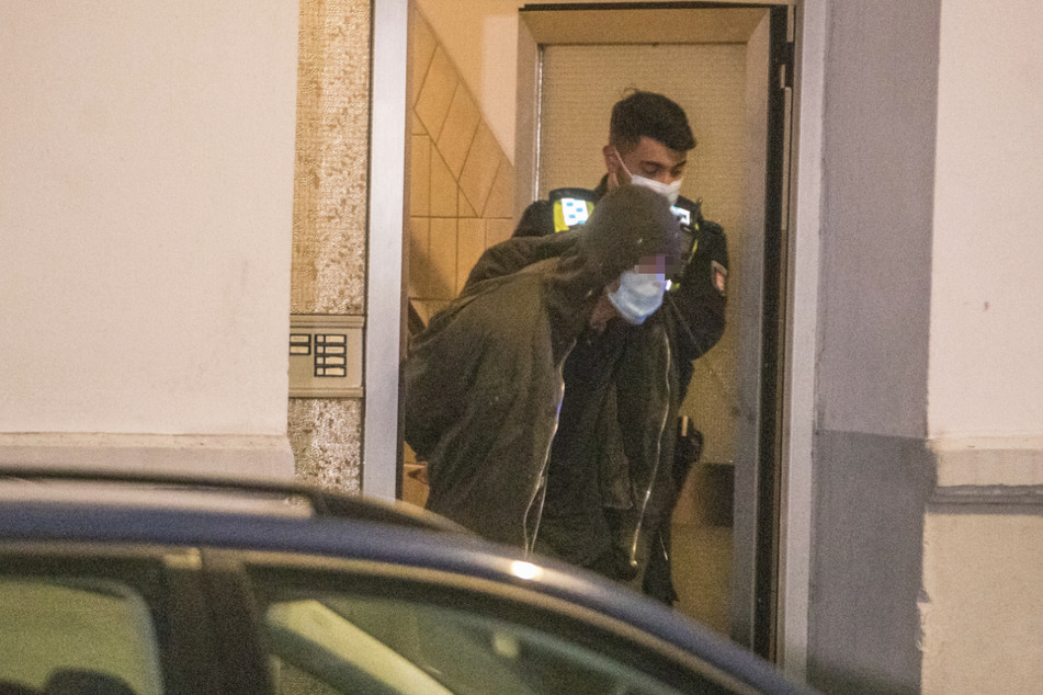 Ein Polizist führt den Mann ab.
