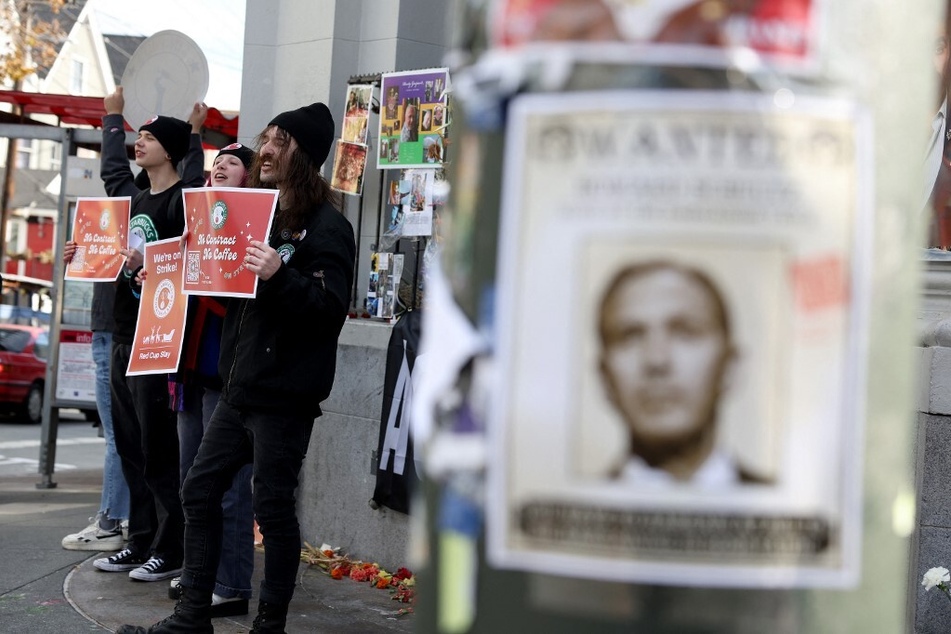 Starbucks workers hold signs outside of a coffee shop as a photo of interim CEO Howard Schultz is posted nearby during a national strike in San Francisco, California.