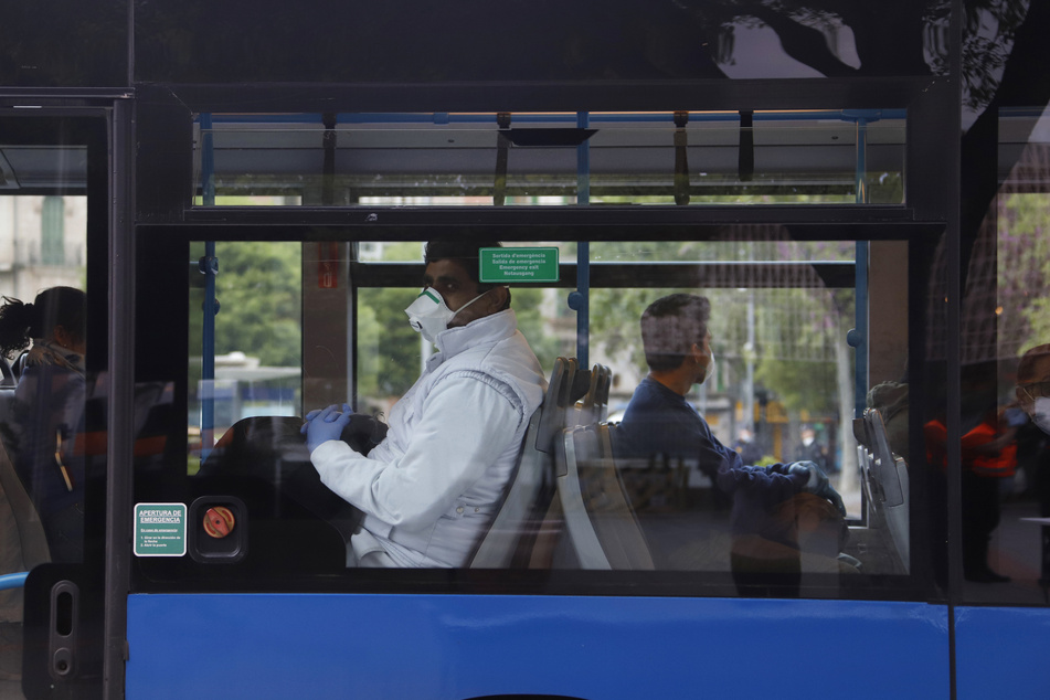 Fahrgäste mit Mund-Nasen-Schutz sitzen am Bahnhof "Intermodal" in Palma in einem Bus.