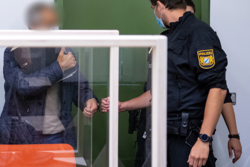 Der Angeklagte wird von Polizisten in den Gerichtssaal geführt.