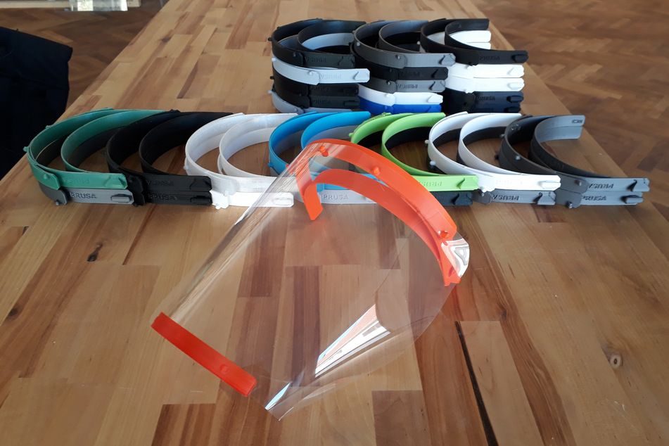 Die Bestandteile von Behelfsvisieren liegen auf einem Tisch, nachdem sie zuvor von einem 3D-Drucker erstellt wurden.