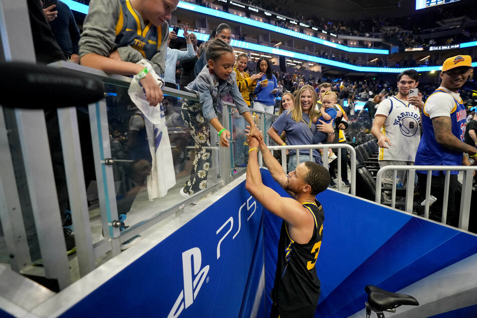 Steph Curry reaches up to his daughter Ryan at the end of the Warriors' win over the Nuggets.
