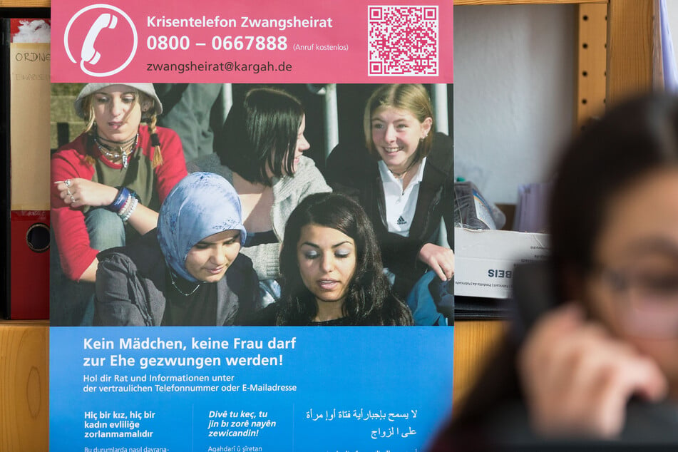Eine Mitarbeiterin des niedersächsischen Krisentelefons führt ein Telefongespräch. Im Hintergrund sieht man das Plakat mit der Aufschirft: "Kein Mädchen, keine Frau darf zur Ehe gezwungen werden!"