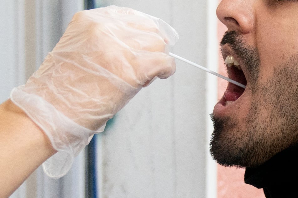Ein Patient lässt vor einer Arztpraxis einen Abstrich für einen PCR Corona-Test machen.