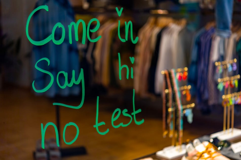 Die Worte "Come in - Say hi - no test" sind auf der Schaufensterscheibe eines Modeladens im Münchner Stadtteil Haidhausen zu lesen.