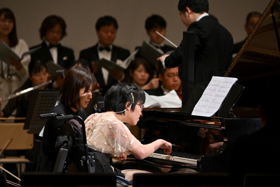 Kiwa Usami (c.), who has cerebral palsy and performs with one index finger, plays an AI-powered piano during a Christmas concert rehearsal of Beethoven’s Symphony No. 9 with the Yokohama Sinfonietta orchestra in Tokyo, Japan.