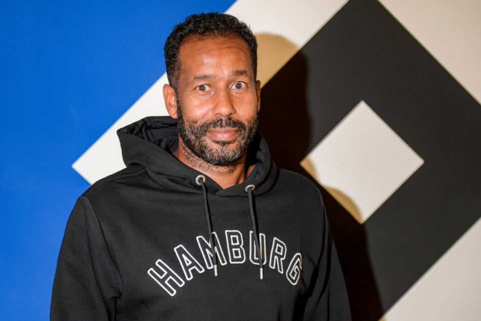 Daniel Thioune, neuer Trainer des Hamburger SV, steht vor dem Vereinslogo