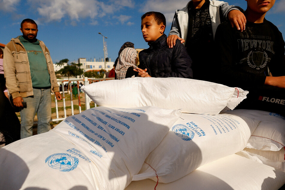 Besieged Palestinians receive flour bags distributed by UNRWA in Rafah, in the southern Gaza Strip.