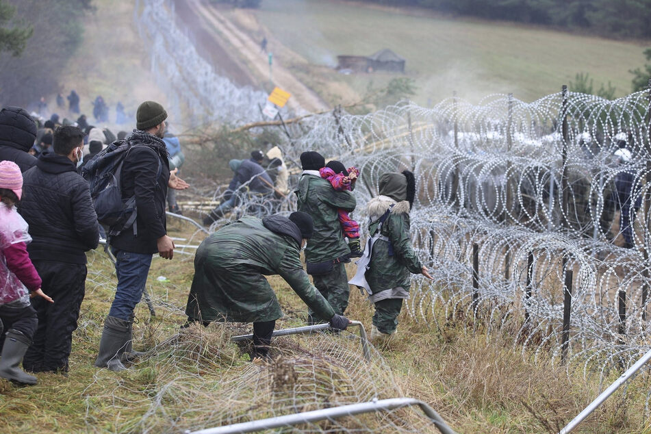 Migranten kommen an der belarussisch-polnischen Grenze an. Ein Stacheldrahtzaun soll den Grenzübertritt verhindern.