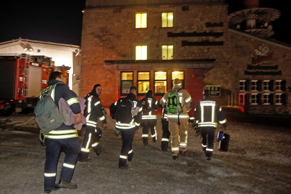 Einsatzkräfte der Feuerwehr gehen in der Nacht in ihre Unterkünfte im Brockenhotel. Ihre Waldbrandbekämpfung aus der Luft hat endlich Wirkung gezeigt.