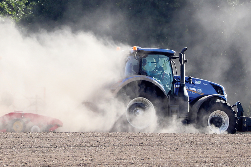 Ein Traktor fährt mit einer Sämaschine über ein Feld bei Grimma.