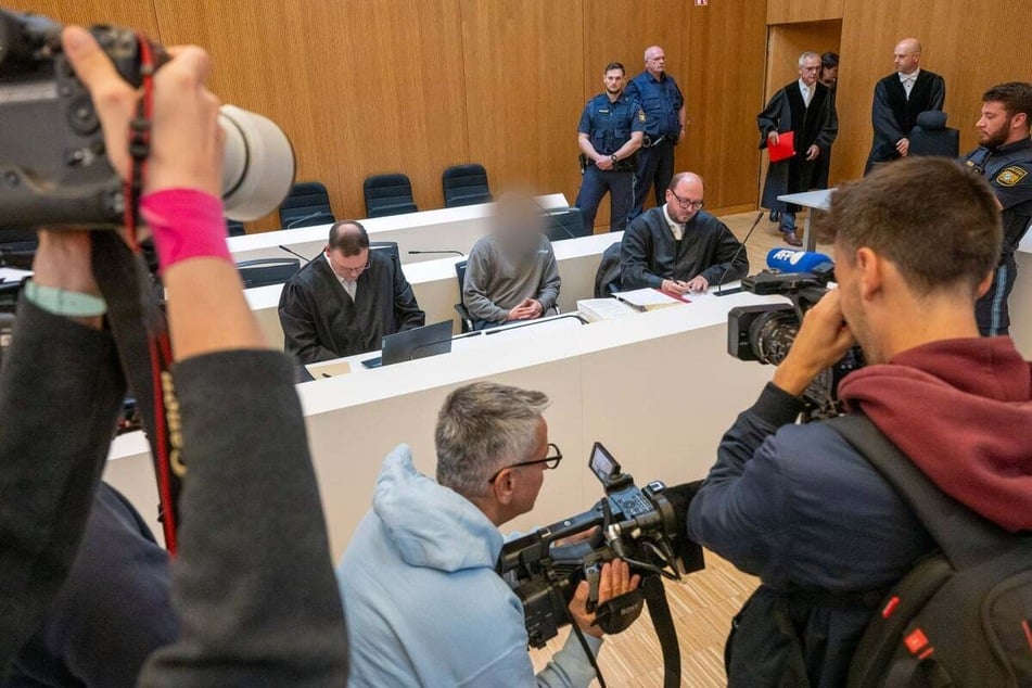 Einer der Angeklagten (M.) sitzt zwischen seinen Anwälten Stephan Schultheis (l.) und Michael Löwe (r.).