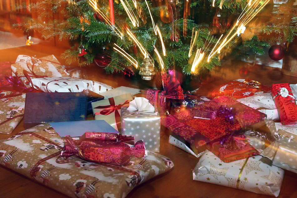 Verpackte Weihnachtsgeschenke liegen unter einem Christbaum. (Symbolbild)