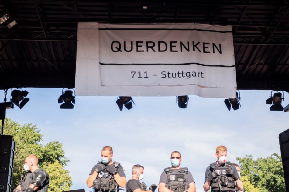Polizisten stehen bei einer Kundgebung gegen die Corona-Beschränkungen auf der Straße des 17. Juni in Berlin auf der Bühne unter dem Banner der Initiative "Querdenken 711".