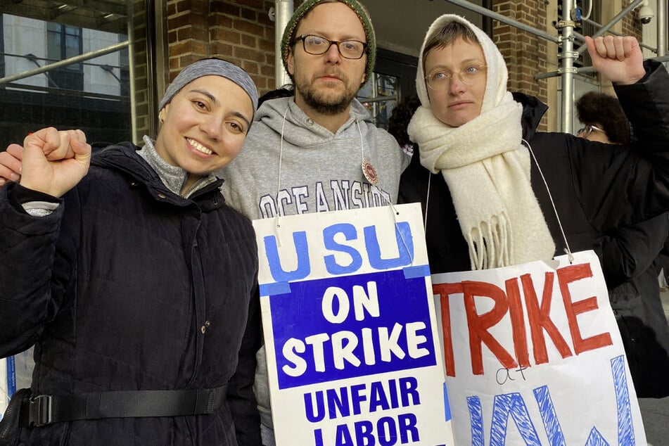 UAW Staff United members raise their fists on the picket line outside the union's office in Manhattan.