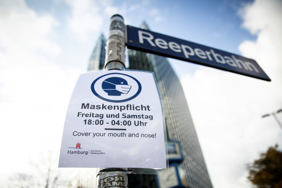 Ein Schild weist auf die Maskenpflicht an der Reeperbahn hin.