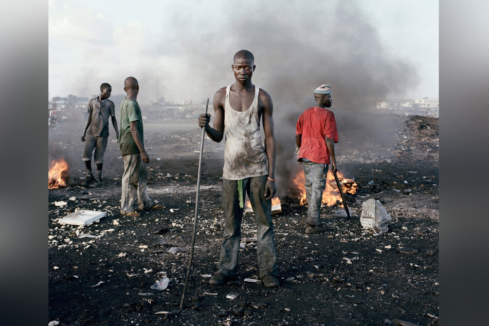 Pieter Hugo zeigt auch David Akore bei der Arbeit auf einer Schrotthalde in Ghana. Giftiger Qualm steigt aus den Schwefelfeuern auf, in denen Reste brennen.