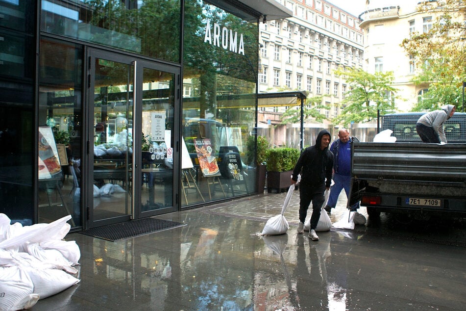 Le persone posizionano sacchi di sabbia all'ingresso di un ristorante a Praga in preparazione all'imminente alluvione.