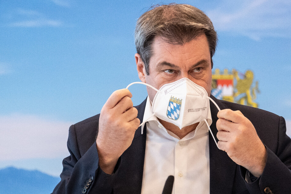 Markus Söder (CSU), Parteivorsitzender und Ministerpräsident von Bayern, nimmt zu Beginn einer Konferenz seine FFP2-Maske ab.