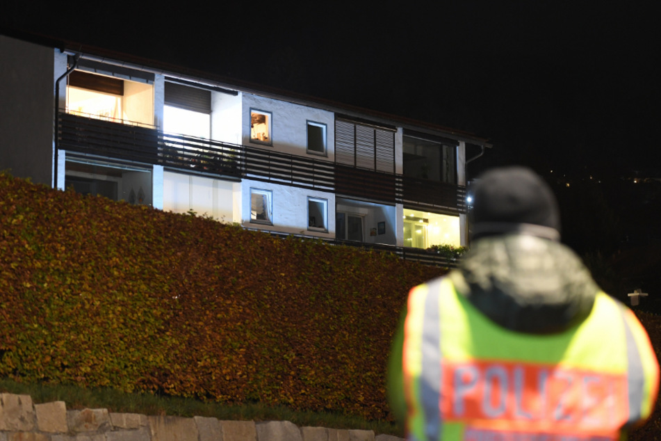 Ein Polizist steht vor dem Mehrfamilienhaus in Tegernsee in dem sich die schreckliche Tat abspielte.