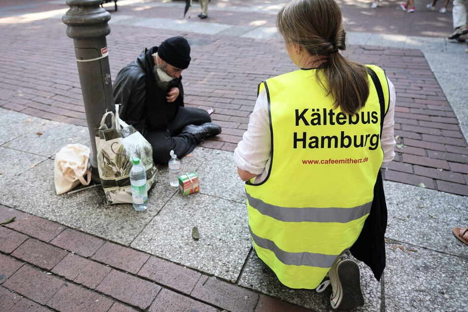 Christina Pillat-Prieß, Koordinatorin des Kältebusses, überreicht einem Obdachlosen am Bahnhof Altona ein Getränk. Der Kältebus war am Mittwoch mit Kaltgetränken, Sonnenschutzmitteln und Obst unterwegs.