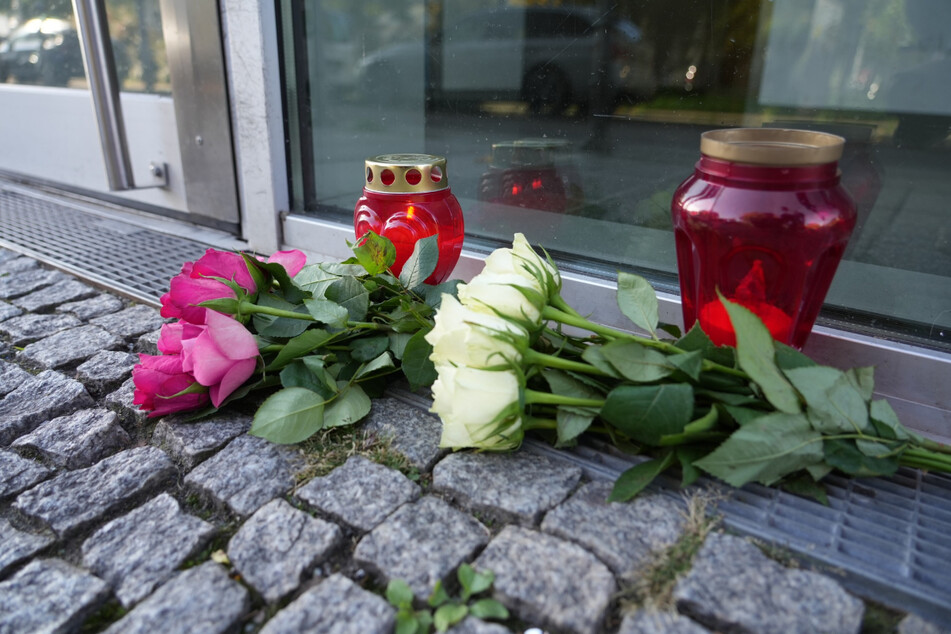 Blumen und Kerzen erinnern am Hauseingang an die Bluttat.