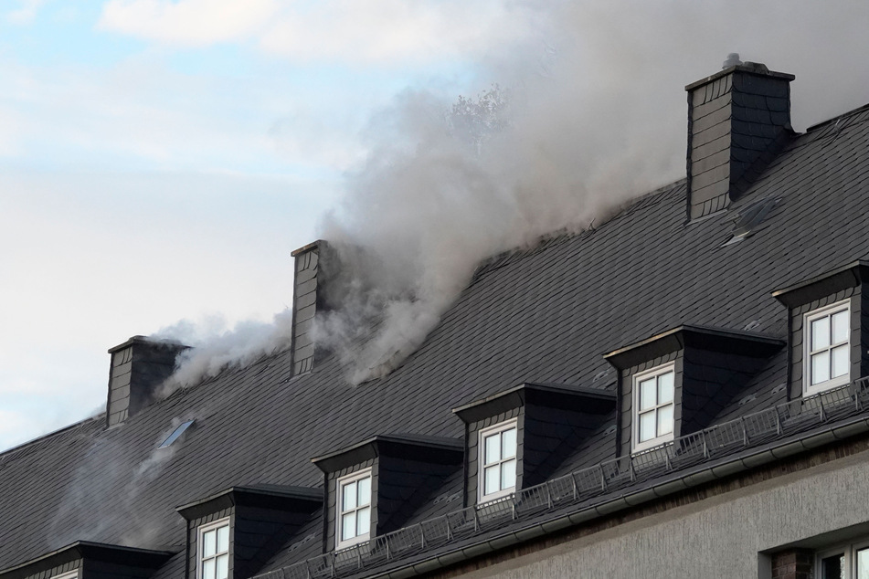 Aus dem Dach des Mehrfamilienhauses stiegen dunkle Rauchwolken auf.