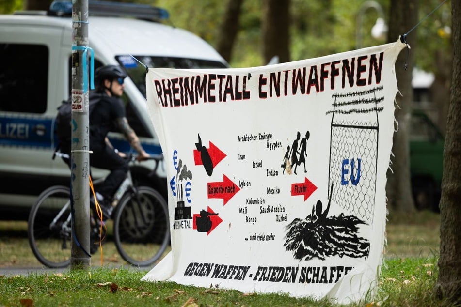 "Rheinmetall Entwaffnen" steht auf einem Plakat am Eingang zum Protestcamp des Bündnisses "Rheinmetall Entwaffnen" im Grüngürtel.