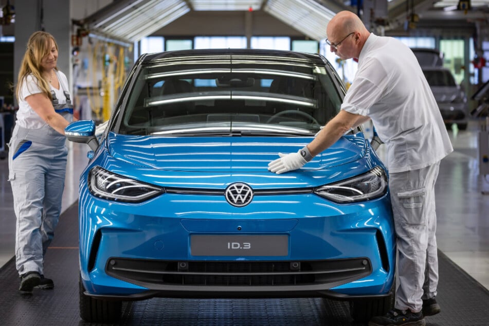 Zwei VW-Mitarbeiter prüfen die Qualität eines VW ID.3 in einer Montagehalle in Zwickau. Aufgrund der schwachen Nachfrage nach E-Autos plant der Autobauer einen enormen Stellenabbau.