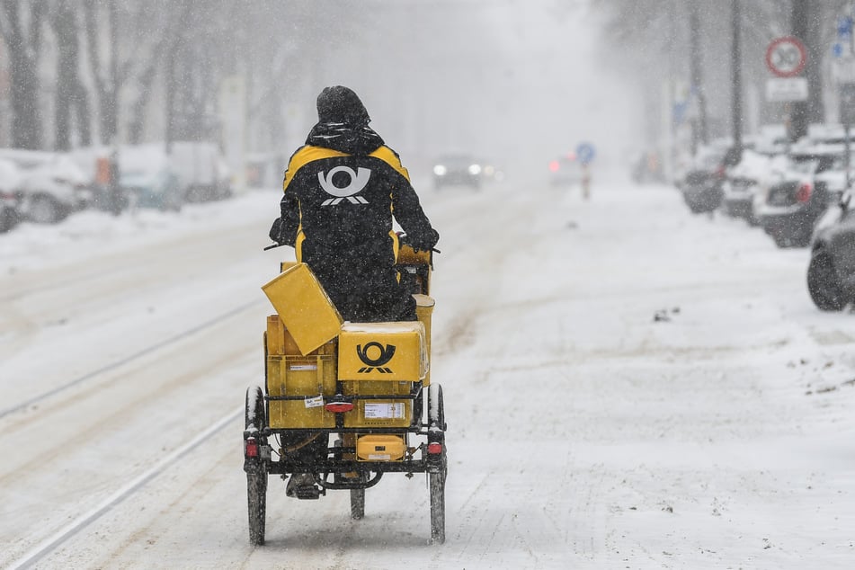 Ein Postbote muss sich per Rad durch den Schnee kämpfen.