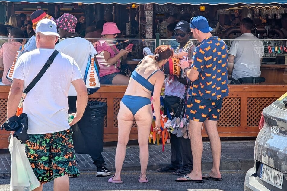 Zielgerichtet schnappt sich Carola (40, im Bikini) einen Hut...