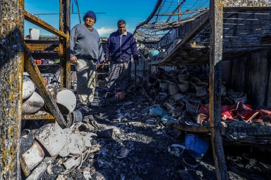 Palestinians inspect the damage at a shop on January 21, 2025, after it was burned in overnight Israeli settler attacks in Jinsafot village, east of Qalqiliya, in the occupied West Bank.