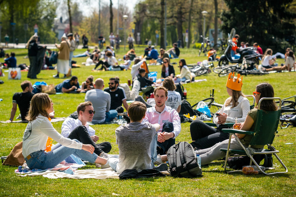 Eindhoven: Menschen sitzen am Königstag im Park Anne Frankplantsoen auf einer Wiese. Noch ist in den Niederlanden Lockdown.