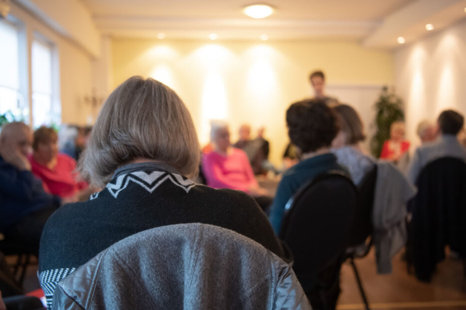 Besucher des "Cafe Tod" sitzen mit Kaffee und Kuchen an Tischen.