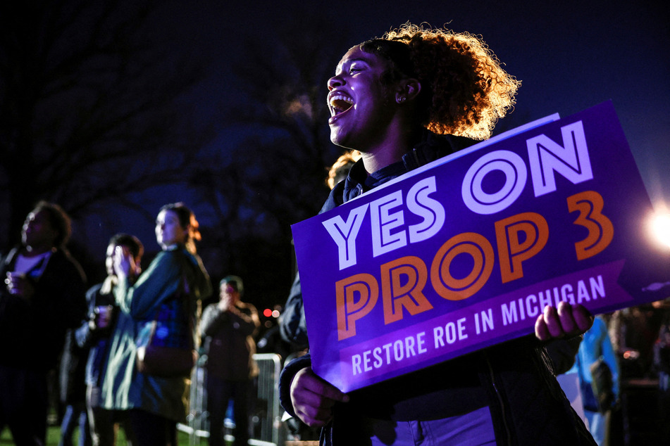 Jaelynn Smith, a freshman at Michigan State University, holds a sign in support of Proposal 3 during a get out the vote rally in East Lansing the night before the midterm election.