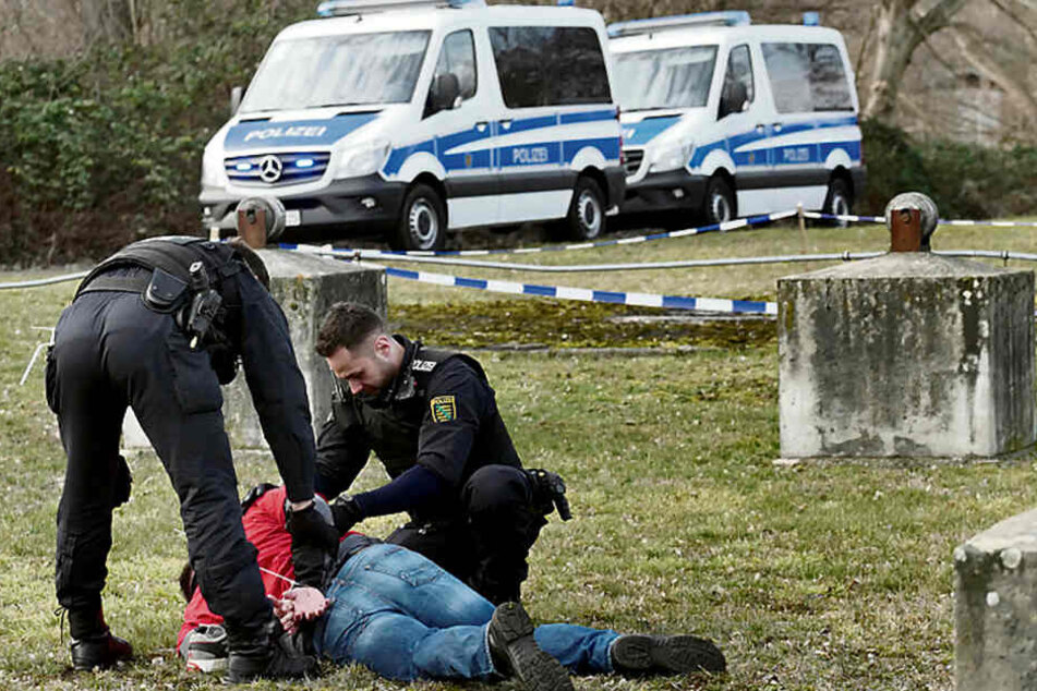 Zwei Bereitschaftspolizisten haben nach einem simulierten Straßenraub unter Jugendlichen einen Verdächtigen am Boden fixiert.