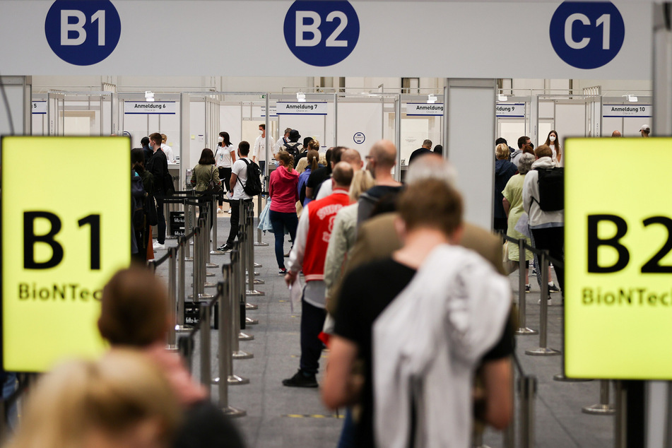 Zahlreiche Impflinge warten in einer Schlange in den Messehallen auf ihre Impfung.