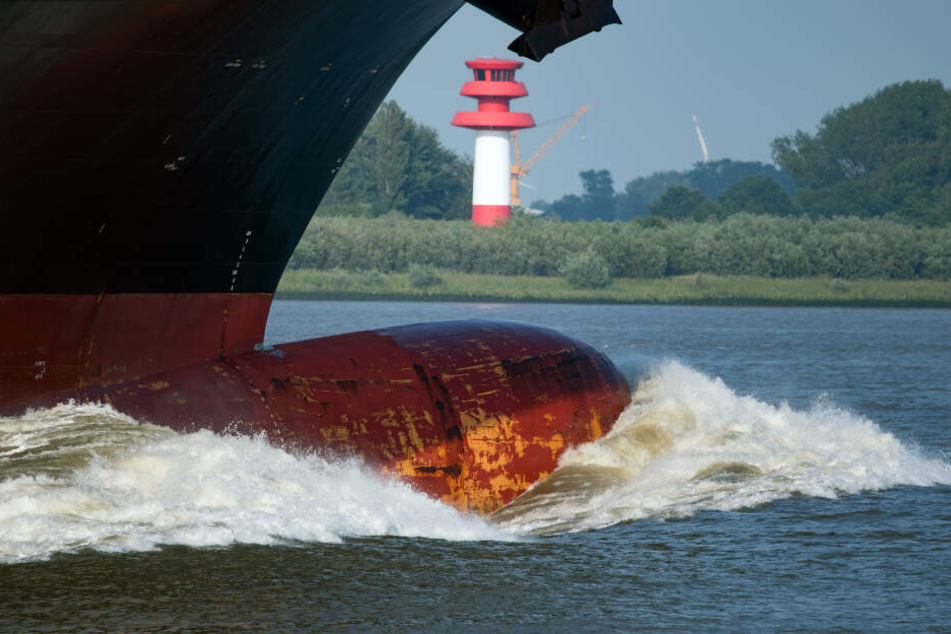 Der Bug eines Containerfrachters schiebt vor der Hafeneinfahrt in Hamburg eine große Welle vor sich her.