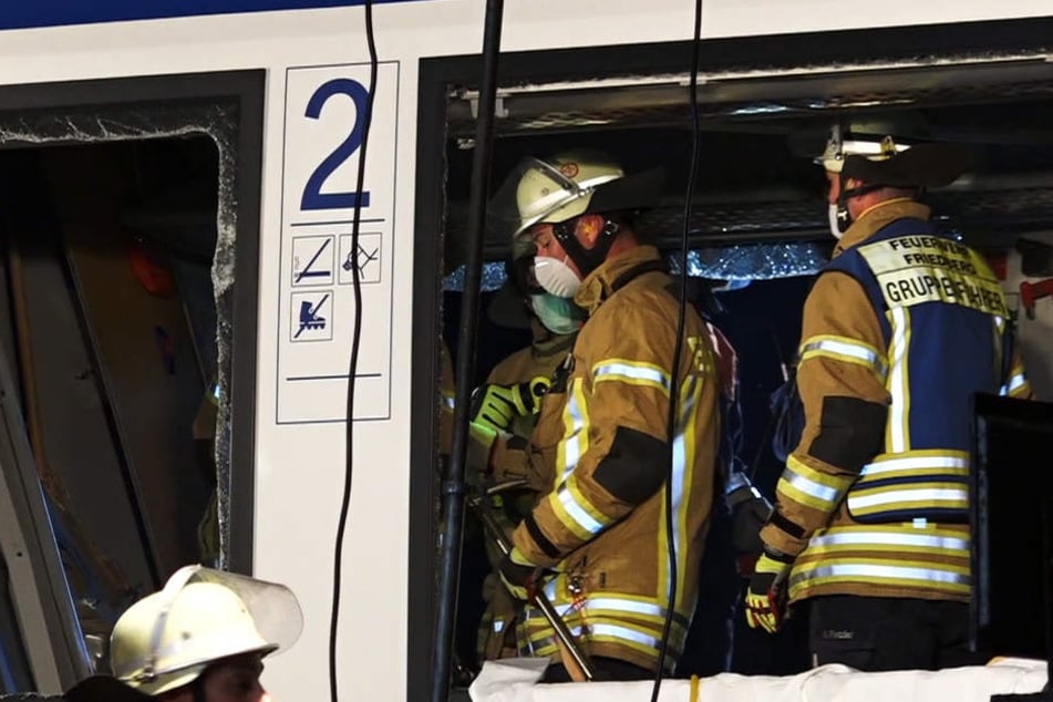 Rettungskräfte stehen in dem Wrack des Personenzuges.
