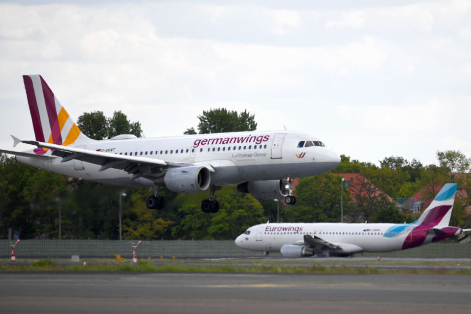 Ein Flugzeug der Airline Germanwings landet auf dem Flughafen Tegel, während im Hintergrund ein Flugzeug der Airline Eurowings auf dem Rollfeld steht. (Archivbild)