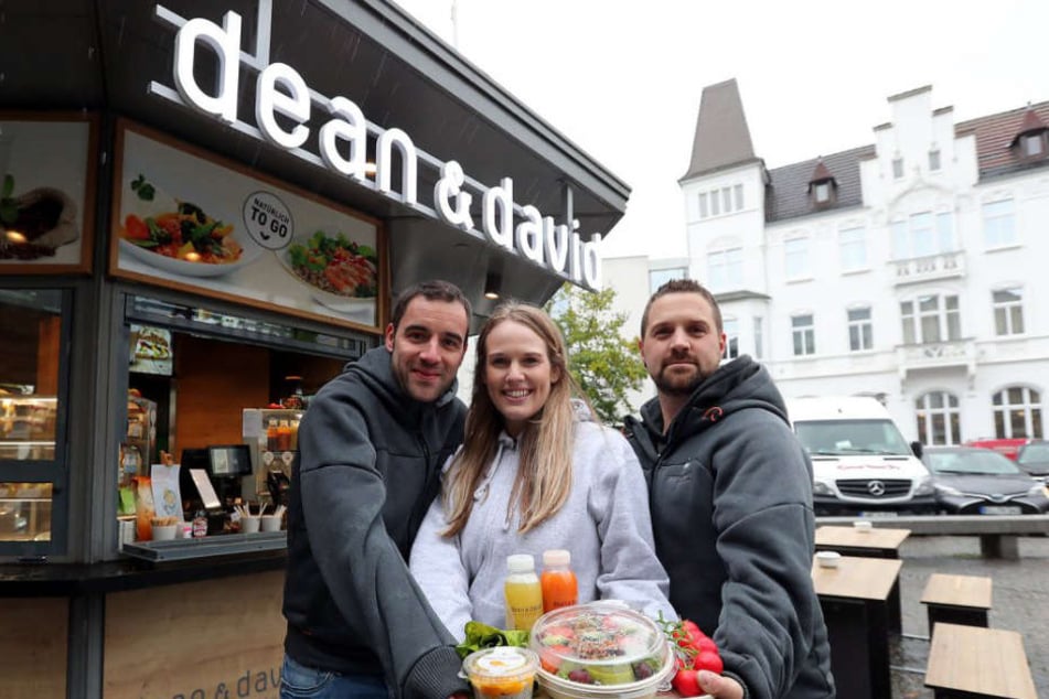 Jonas Vorbohle (l.), Mitarbeiterin Frederieke Hückelheim und Marco Schirrmeister präsentieren die To-go-Produkte.