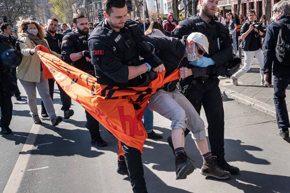 Polizisten führen einen Demonstranten zur Aufnahme der Personalien ab.