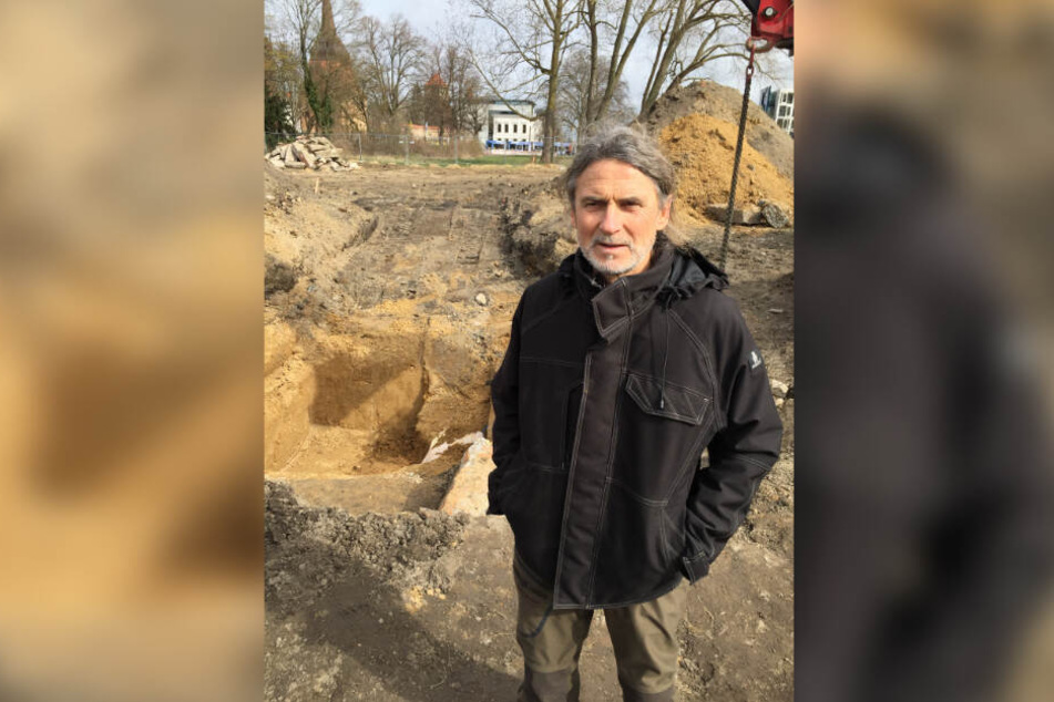 Fred Tribanek vom Munitionsbergungsdienst M.-V. steht vor einem tiefen Loch in der Rostocker Innenstadt in dem eine 250 Kilogramm-Fliegerbombe liegt, die mit Plastik abgedeckt wurde.