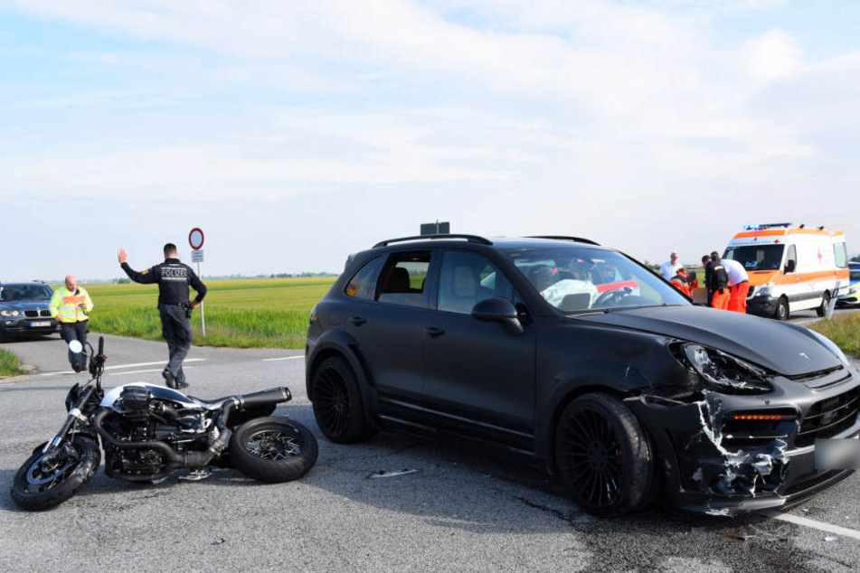 Das Motorrad liegt neben dem Porsche auf der Straße.